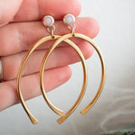 Load image into Gallery viewer, Gold hoop earrings held by a hand against a neutral background
