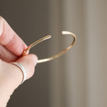 Load image into Gallery viewer, Brass bangle held by a hand against a neutral background
